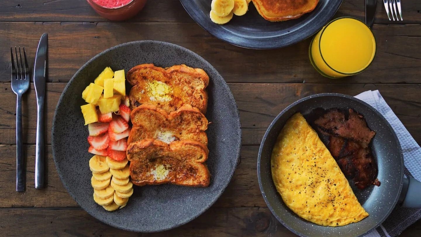 Full brunch plate · french toast with fresh fruit, omelette, bacon, orange juice and pancakes